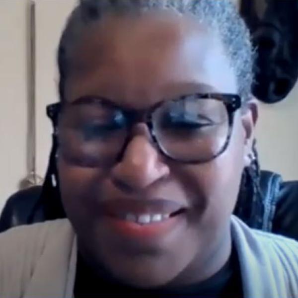 Black woman graying black hair with  glasses smiles 